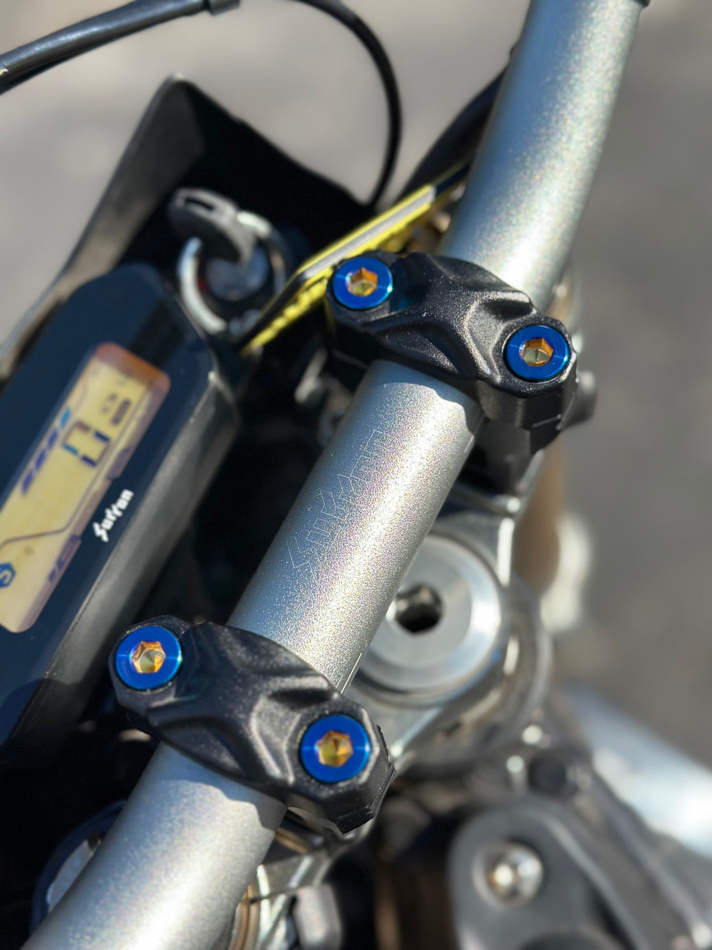 Close up picture of Surron Ultra Bee handlebar clamp with blue titanium bolts
